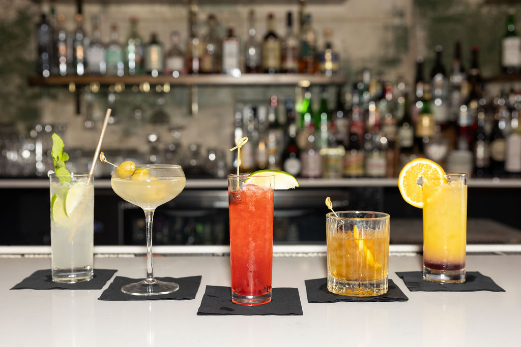 Five signature cocktails lined up on the bar