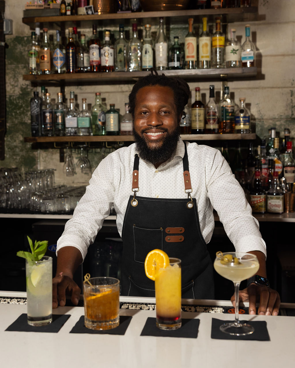 Daniel smiling behind four finished cocktails